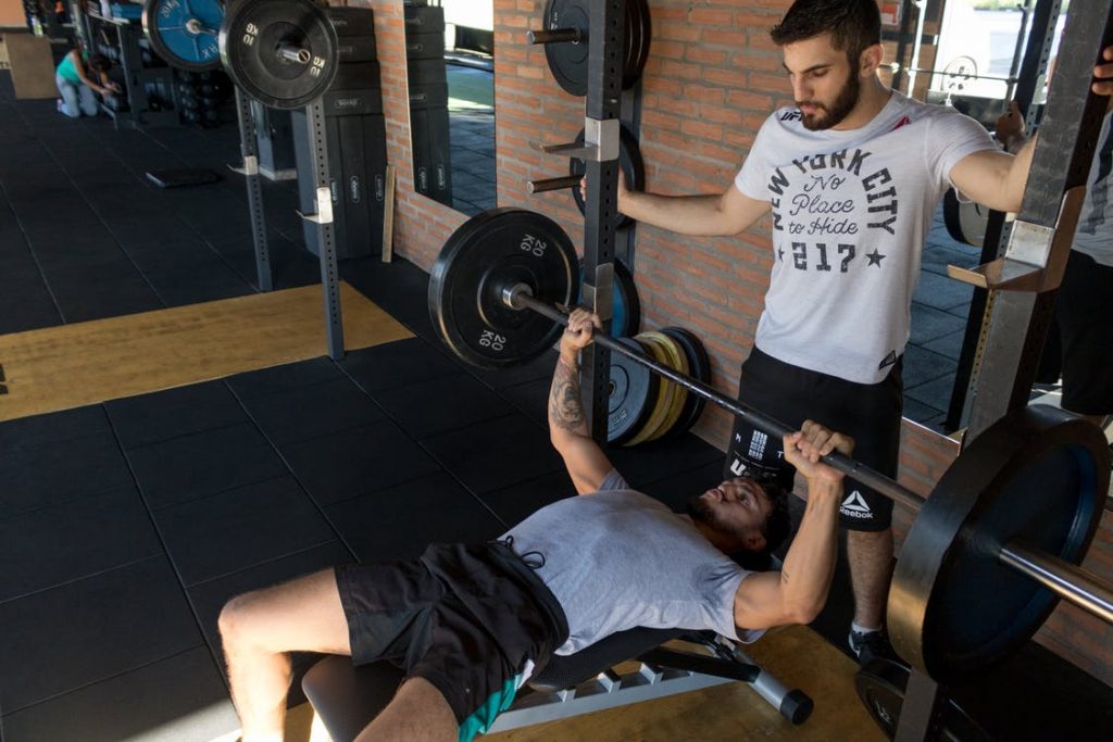 Personal trainer begeleidt klant bij personal training in de sportschool met deskundig advies